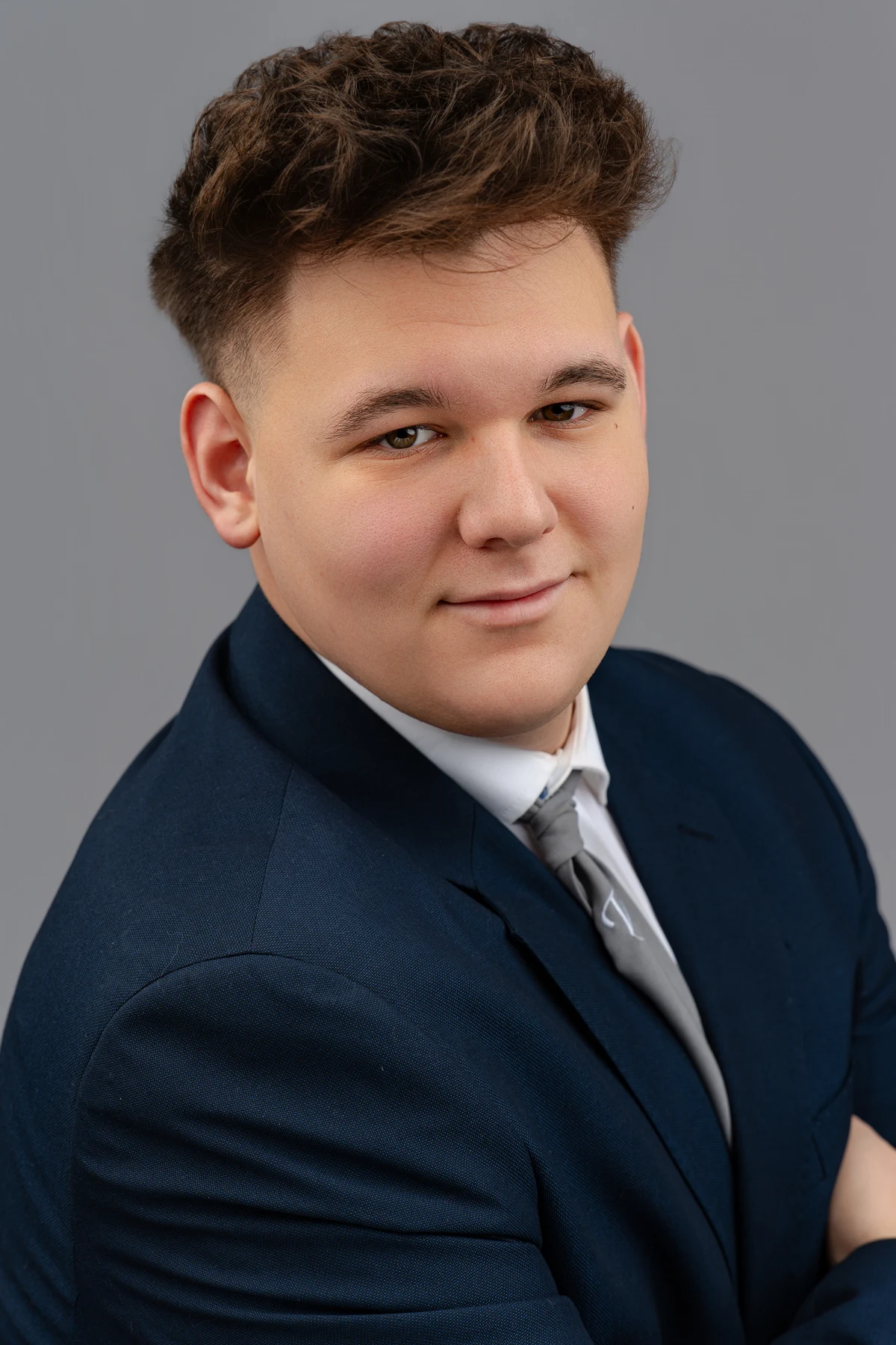 Végzős diák portréja szürke háttér előtt